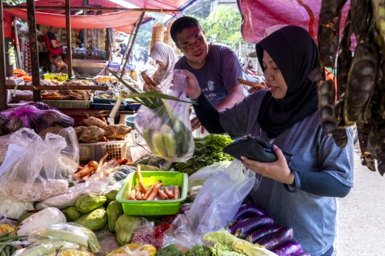 Une cliente (d) achète des légumes sur un étal d'un marché à Jakarta, le 3 juin 2026 en Indonésie ( AFP / BAY ISMOYO )