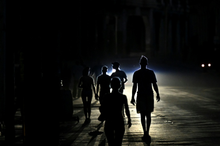 Des habitants marchent dans une rue de La Havane pendant une panne d'électricité, le 13 mai 2026 à Cuba ( AFP / Yamil LAGE )