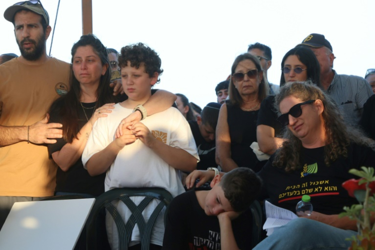 La femme (D) et le fils de l'otage israélien Tal Haimi tué par des combattants palestiniens durant l'attaque du 7-Octobre, pleurent lors de ses funérailles au kibboutz Nir Yitzhak, dans le sud d'Israël, le 22 octobre 2025 ( AFP / GIL COHEN-MAGEN )