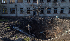 Un soldat ukrainien sort d'un cratère d'obus devant un bâtiment près de la ville de Lyman