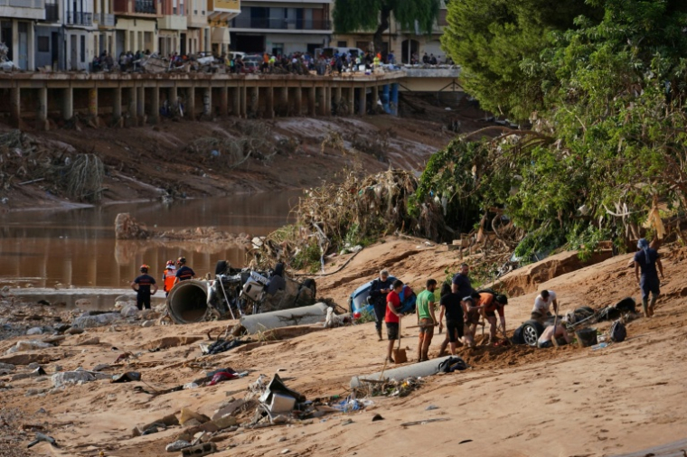 Des personnes tentent de dégager une voiture engloutie par la boue à la recherche de victimes, après les inondations qui ont frappé la région de Valence, le 1er novembre 2024 à Paiporta, en Espagne ( AFP / Manaure Quintero )
