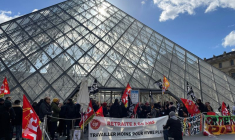 Des manifestants portant des drapeaux CGT et Sud Culture Solidaires se tiennent devant la Pyramide du Louvre
