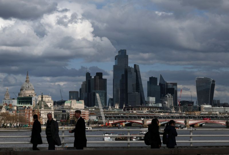 Des personnes traversent le pont de Waterloo avec les gratte-ciel du quartier financier de la City de Londres et la cathédrale Saint-Paul visibles en arrière-plan, à Londres