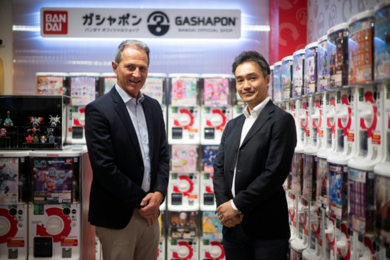 Le patron de l'enseigne française de jouets King, Philippe Gueydon (à gauche) et son homologue de Bandai Europe, Koji Iwata, dans la première boutique française dédiée aux jouets "encapsulés" dans des balles en plastique, vendus dans des machines, à Paris, le 2 avril 2026 ( AFP / JULIEN DE ROSA )
