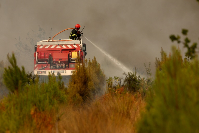 Un pompier arrose de la végétation dans la zone d'un feu de forêt Blagon, à l'ouest de Bordeaux, le 26 juillet 2026  ( AFP / ROMAIN PERROCHEAU )