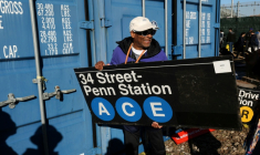 Le réalisateur Spike Lee tient une panneau d'une station de métro qu'il vient d'acheter lors de la vente annuelle organisée par la régie des transports de New York (MTA), le 9 octobre 2026 ( AFP / TIMOTHY A. CLARY )
