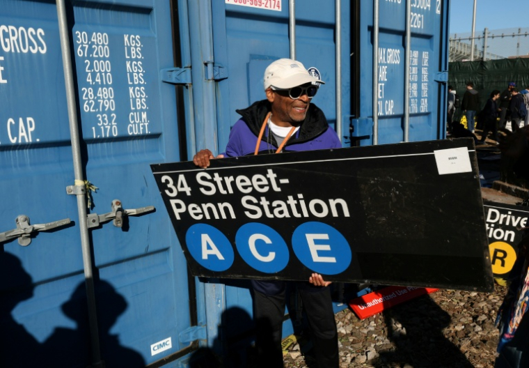 Le réalisateur Spike Lee tient une panneau d'une station de métro qu'il vient d'acheter lors de la vente annuelle organisée par la régie des transports de New York (MTA), le 9 octobre 2026 ( AFP / TIMOTHY A. CLARY )