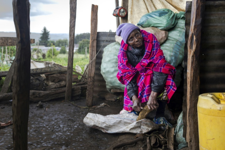 Janet Sumpet Ngusilo, grand-mère du militant des droits de l'homme de la communauté Ogiek Fred Ngusilo, prépare un repas à l'extérieur de la chambre qu'elle loue à Oloikirikirai où elle vit depuis que sa communauté a été expulsée de la forêt de Mau, dans le comté de Narok, le 16 août 2025 au Kenya ( AFP / Tony KARUMBA )