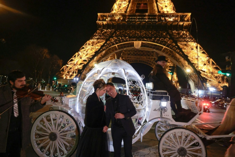 Le couple néerlandais Shirley Wijgaarts et Sander Castel (g) devant un carrosse digne d'un conte de fées, lors de leur demande en mariage, devant la Tour Effeil à Paris, le 7 février 2026 ( AFP / STEPHANE DE SAKUTIN )