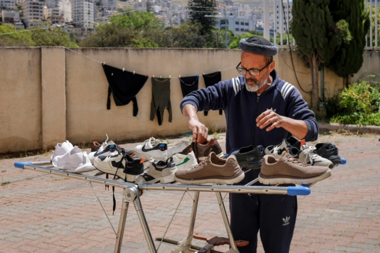 Samir Abou Salah, un Palestinien de Gaza, fait sécher des chaussures dans un stade où il a dû s'installer, à Naplouse, dans le nord de la Cisjordanie occupée, le 7 mai 2026 ( AFP / Zain JAAFAR )