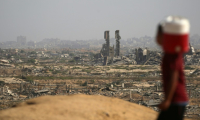 Un enfant palestinien portant un bidon d'eau passe devant des destructions sur une route côtière au nord-ouest du camp de Nousseirat, empruntée par des Palestiniens déplacés se rendant vers le sud de la bande de Gaza, le 4 octobre 2025 ( AFP / Eyad BABA )