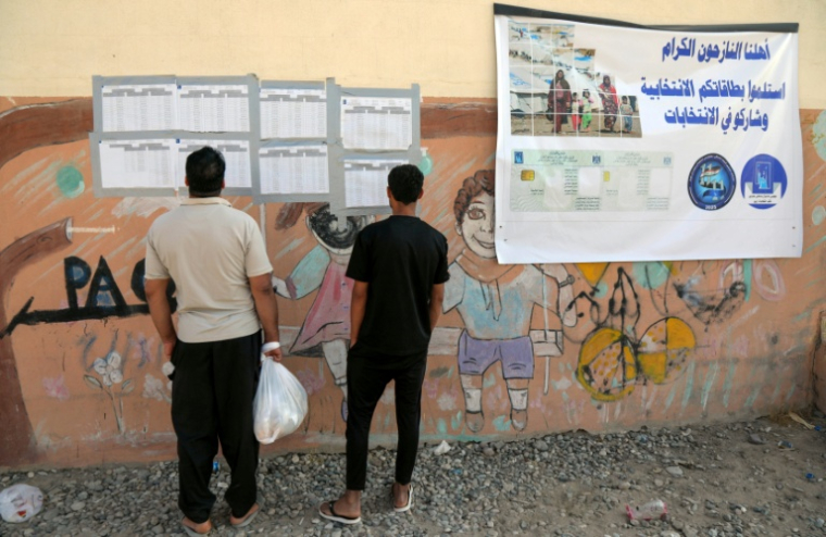 Des Irakiens déplacés consultent les listes nominatives affichées à l'extérieur d'un bureau de vote, à l'arrivée pour voter avant les élections législatives du 11 novembre, dans un camp du nord de l'Irak, le 9 novembre 2025 ( AFP / Safin HAMID )