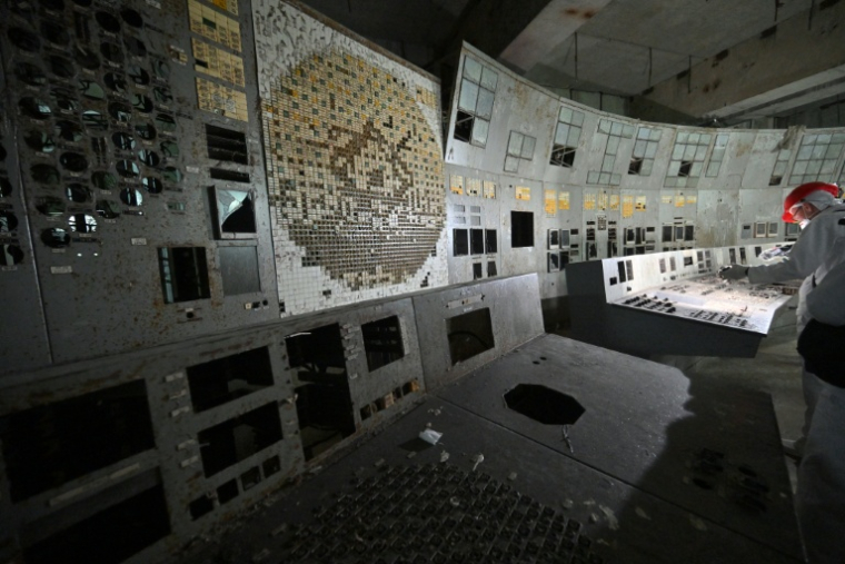 Un visiteur de la centrale nucléaire de Tchernobyl filme dans la salle de contrôle du bloc 4 détruit de la centrale, le 23 avril 2026 ( AFP / Sergei SUPINSKY )