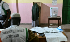 Une personne vote lors des élections législatives en Côte d'Ivoire, sous la surveillance d"un membre de la commission électorale indépendante, à  Abidjan le 27 décembre 2025 ( AFP / Sia KAMBOU )
