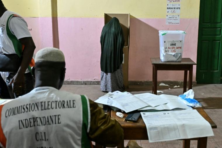 Une personne vote lors des élections législatives en Côte d'Ivoire, sous la surveillance d"un membre de la commission électorale indépendante, à  Abidjan le 27 décembre 2025 ( AFP / Sia KAMBOU )