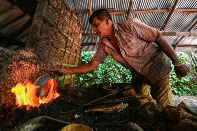 Le forgeron Thenuwara Badalge Sarath fabrique des bols utilisés par les moines bouddhistes pour solliciter l'aumône dans un village de Panvila, au Sri Lanka, le 2 juin 2025 ( AFP / Ishara S. KODIKARA )