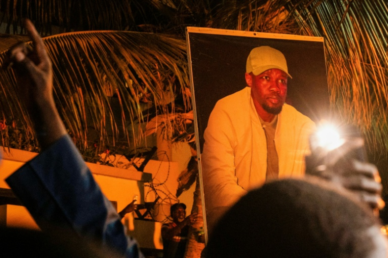 Des partisans d'Ousmane Sonko brandissent son portrait devant son domicile de Dakar, le 23 mai 2026 ( AFP / SEYLLOU )