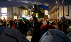 Un manifestant regarde son téléphone à côté de tentes dans le campement en établi en protestation contre les expulsions et la crise du logement sur la Puerta del Sol, à Madrid, le 27 septembre 2026 ( AFP / Oscar DEL POZO )