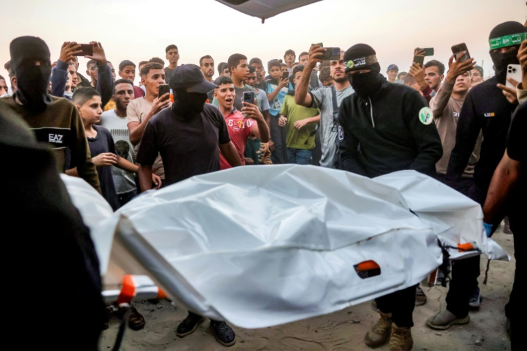 Des Palestiniens regardent des combattants du Hamas transporter un corps retrouvé dans un tunnel vers une ambulance dans une zone située au nord de Khan Younès, dans le sud de la bande de Gaza, le 28 octobre 2025 ( AFP / Bashar TALEB )