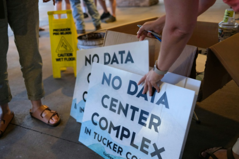 Des bénévoles distribuent des pancartes anti-data center en marge d'une réunion publique à Canaan Valley, en Virginie occidentale, le 30 juin 2025 ( AFP / Ulysse BELLIER )