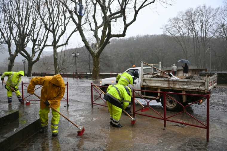 Des employés municipaux nettoient une rue après la crue de l'Hérault suite aux fortes pluies à Laroque, le 22 décembre 2025 ( AFP / Sylvain THOMAS )