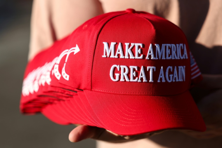 Un membre de Turning Point USA distribue des casquettes "MAGA" aux personnes rassemblées devant un mémorial improvisé en hommage à Charlie Kirk, fondateur de Turning Point USA, devant le siège de l'organisation à Phoenix, en Arizona, le 19 septembre 2025 ( AFP / CHARLY TRIBALLEAU )