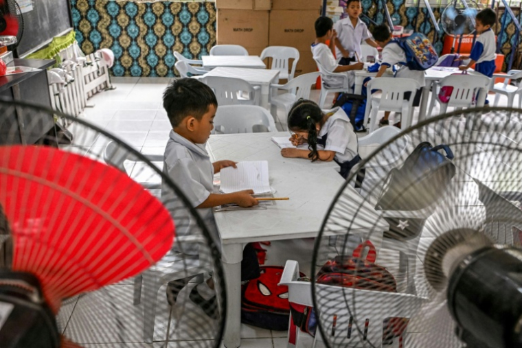 Des élèves d'école primaire travaillent à l'aide de ventilateur sur l'île de Baseco à Manille, le 21 mars 2025 ( AFP / Jam STA ROSA )