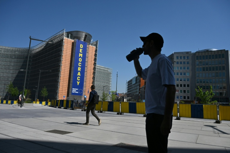 Un homme boit de l'eau, à l'ombre près du bâtiment de la Commission européenne, lors d'une vague de chaleur à Bruxelles, le 25 juin 2026 ( AFP / Nicolas TUCAT )