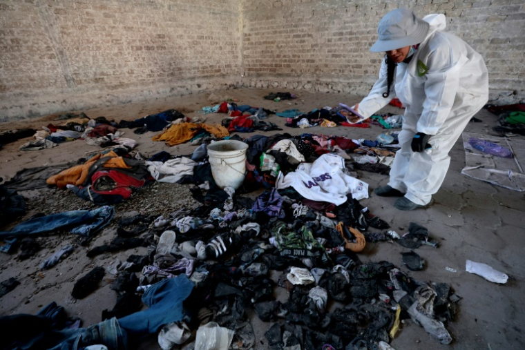 Une femme photographie ou filme des habits et des chaussures retrouvés dans le ranch Izaguirre Ranch à Teuchitlan, dans l'Etat du Jalisco, dans le nord-ouest du Mexique, le 5 mars 2025 ( AFP / ULISES RUIZ )
