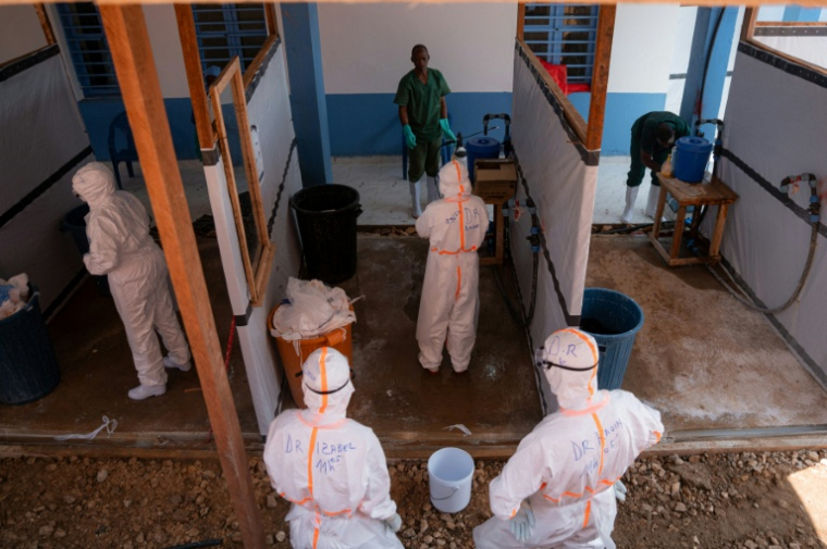 Des membres du personnel médical dans un poste de retrait et de décontamination des équipements de protection après avoir soigné des patients atteints du virus Ebola, à Bunia, dans la province de l'Ituri, le 13 juin 2026 en RDC ( AFP / Jospin Mwisha )
