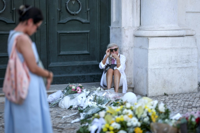 Une femme assise pleure le 5 septembre 2025 près du site où un funiculaire a déraillé à Lisbonne faisant 16 morts ( AFP / PATRICIA DE MELO MOREIRA )
