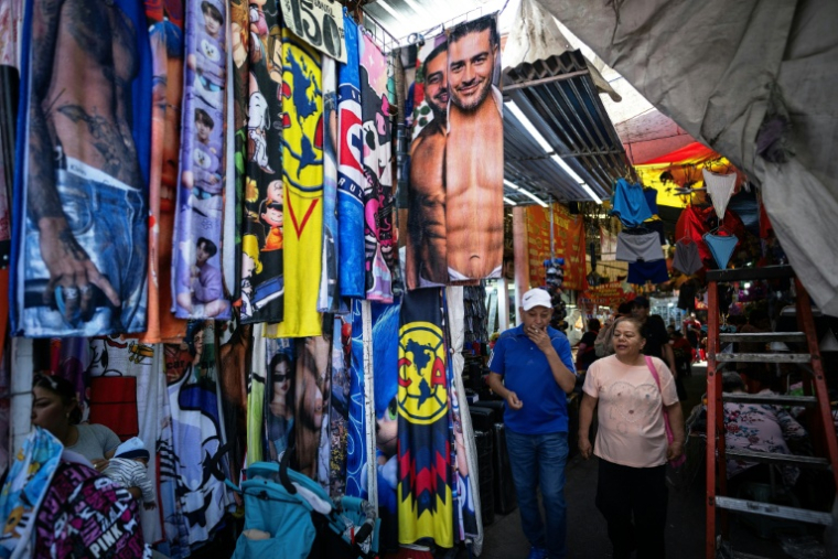Des vendeurs de rue proposent des tee-shirts, serviettes, et autres produits dérivés à l'effigie du minsitre à la sécurité, Omar Garcia Harfuch, à Mexico le 1er mai 2026 ( AFP / CARL DE SOUZA )