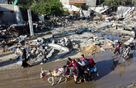 Des Palestiniens déplacés rentrent chez eux et passent devant une maison détruite par une attaque israélienne à Khan Younis, pendant la trêve conclue entre le Hamas et Israël