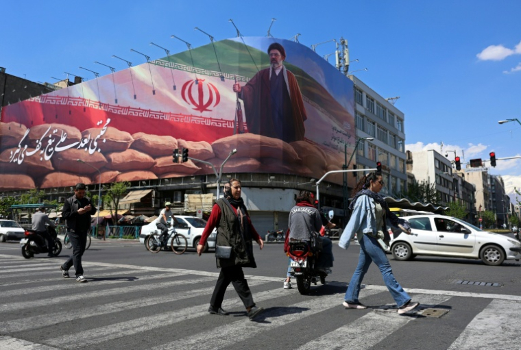 Des piétons traversent une rue devant une affiche géante du guide suprême iranien, l'ayatollah Mojtaba Khamenei, le 10 avril 202 à Téhéran  ( AFP / - )
