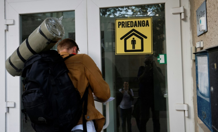 Un bénévole de la protection civile devant l'entrée d'un immeuble lors d'une démonstration concernant les abris antibombes développés en Lituanie, à Vilnius le 21 août 2025 ( AFP / Petras Malukas )