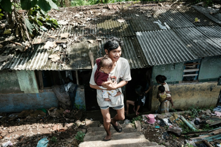 L'artiste de rue Ari Munandar et sa fille devant leur maison à Jakarta, le 7 avril 2025 en Indonésie ( AFP / Yasuyoshi CHIBA )