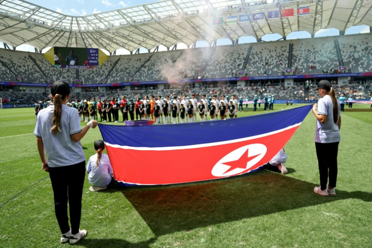 Les joueuses du Bangladesh et de la Corée du Nord derrière le drapeau national nord-coréen avant le coup d'envoi du match de la Coupe d'Asie féminine de l'AFC 2026 en Australie opposant le Bangladesh à la Corée du Nord, à Sydney, le 6 mars 2026 ( AFP / DAVID GRAY )