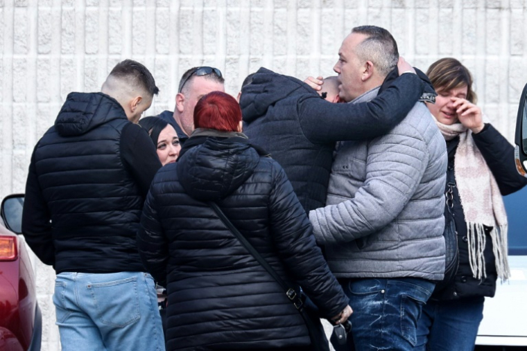 Des personnes rassemblées près d’un gymnase où des témoins et des proches des victimes sont accueillis, à proximité du lieu où une voiture a percuté une foule de carnavaliers, à Strepy-Bracquegnies en Belgique, le 20 mars 2022. ( AFP / Kenzo TRIBOUILLARD )