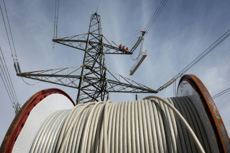 Des apprentis suivent une formation sur un pylône au centre de formation de National Grid à Eakring, dans le centre de l'Angleterre, le 28 avril 2025, perchés à 45 mètres de hauteur ( AFP / Darren Staples )