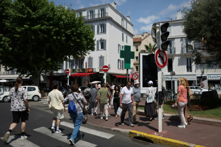 Des piétons dans une rue de Cannes où les feux tricolorent ne fonctionnent pas en raison d'une panne de courant, au dernier jour du 78e Festival de Cannes, le 24 mai 2025 dans les Alpes-Maritimes ( AFP / Sameer AL-DOUMY )