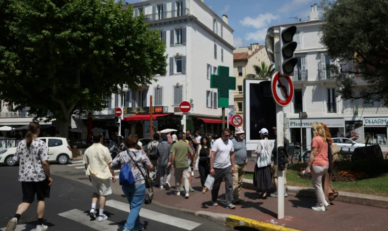 Des piétons dans une rue de Cannes où les feux tricolorent ne fonctionnent pas en raison d'une panne de courant, au dernier jour du 78e Festival de Cannes, le 24 mai 2025 dans les Alpes-Maritimes ( AFP / Sameer AL-DOUMY )