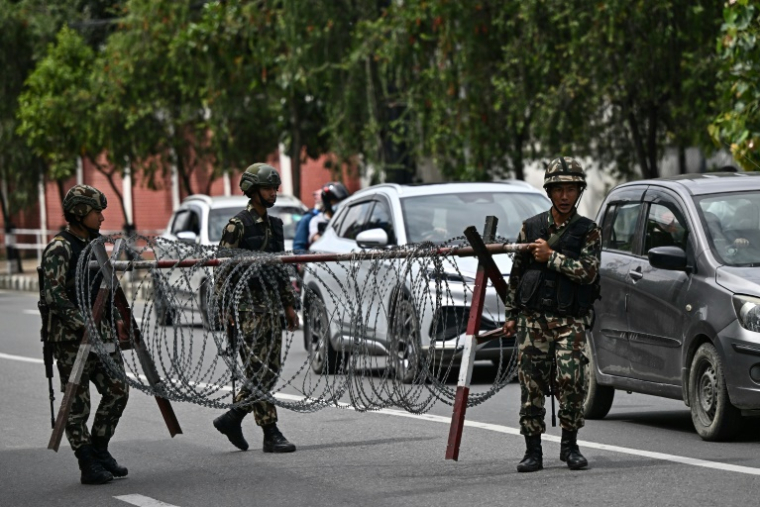 Des militaires déplacent une barrière en barcelés alors qu'ils montent la garde devant la Maison du Président pendant un couvre-feu imposé pour rétablir la loi et l'ordre à Katmandou, le 12 septembre 2025 au Népal ( AFP / Pedro Pardo )