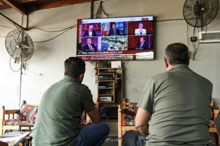 Des hommes regardent l'annonce de la dissolution du PKK sur un écran de TV à Diyarbakir, en Turquie, le 12 mai 2025 ( AFP / Ilyas AKENGIN )