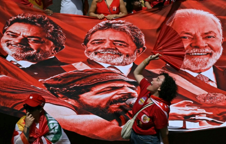 Des partisans du président brésilien de gauche, Luiz Inacio Lula da Silva, devant une bannière géante à son effigie lors d'un meeting de campagne à Rio, le 2 octobre 2026  ( AFP / Luis ROBAYO )