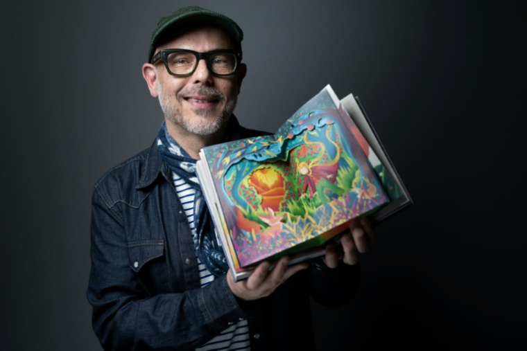 Eduardo Lima du studio MinaLima pose avec le nouvel album du "Petit Prince", le 2 avril 2026 à Paris  ( AFP / JOEL SAGET )