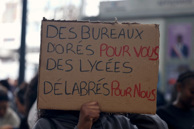 Un élève tient une pancarte lors d'un blocage devant le lycée Paul-Éluard