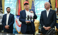 Le président américain Donald Trump, entouré du vice-président JD Vance et du chef de la FIFA Gianni Infantino, montre une photo sur laquelle il figure en compagnie de son homologue russe Vladimir Poutine, le 22 août 2025 à la Maison Blanche ( AFP / ANDREW CABALLERO-REYNOLDS )