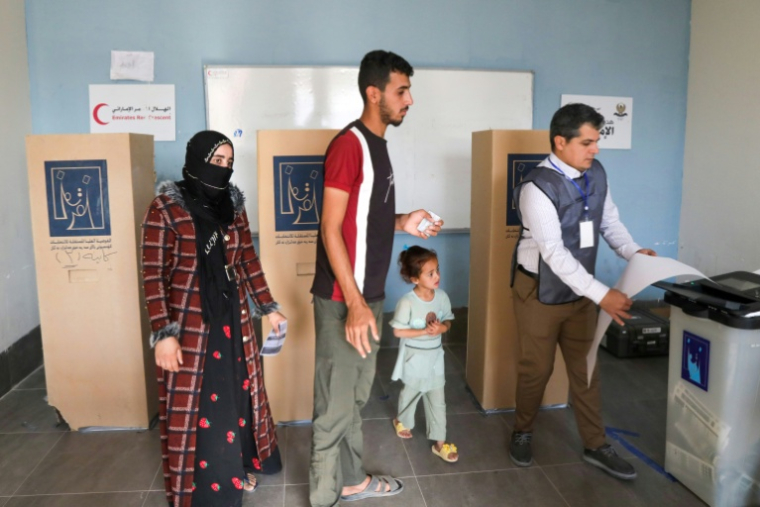 Un Irakien déplacé reçoit de l'aide pour voter dans un bureau de vote avant les élections législatives du 11 novembre, dans un camp du nord de l'Irak, le 9 novembre 2025 ( AFP / Safin HAMID )