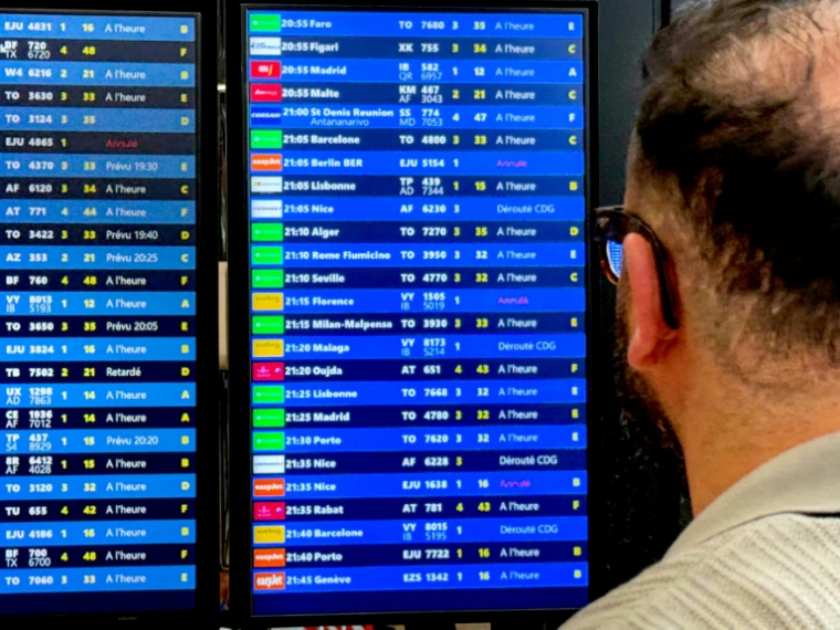 Un voyageur regarde des panneaux d'informatino sur les vols lors d'une panne des systèmes de contrôle aérien à l'aéroport de Paris-Orly, au sud de Paris, le 18 mai 2025 ( AFP / Aurore MESENGE )