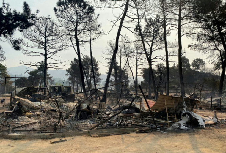 Restes calcinés de caravanes et de tentes dans un camping du Pantano de Burguillo, à El Barraco, à 100 kilomètres à l'ouest de Madrid, le 27 juillet 2026 ( AFP / Roland LLOYD PARRY )